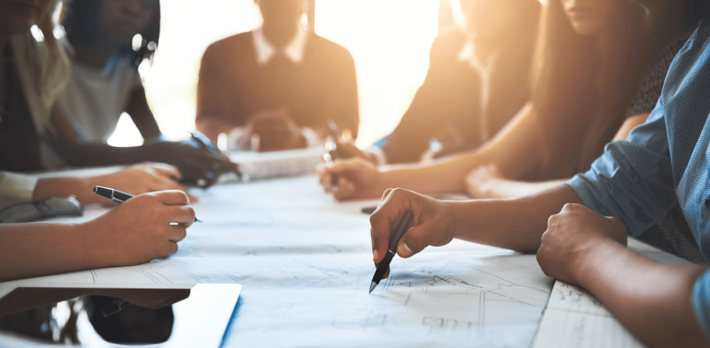 Recruitment and Training Manager - people sitting around a business table having a discussion, sunset background